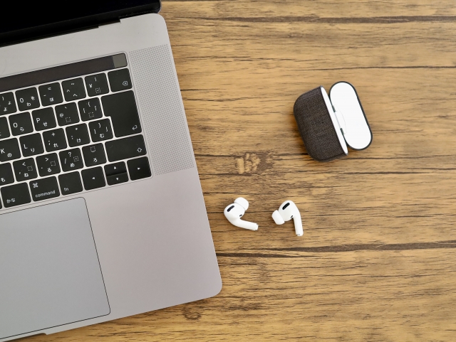 ノートパソコンとワイヤレスイヤホンが並んでいる画像