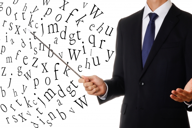 アルファベットを棒で指している男性の画像