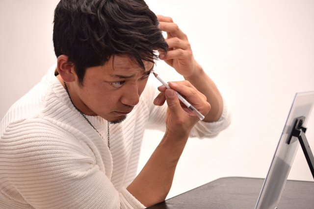 眉毛を書いている男性